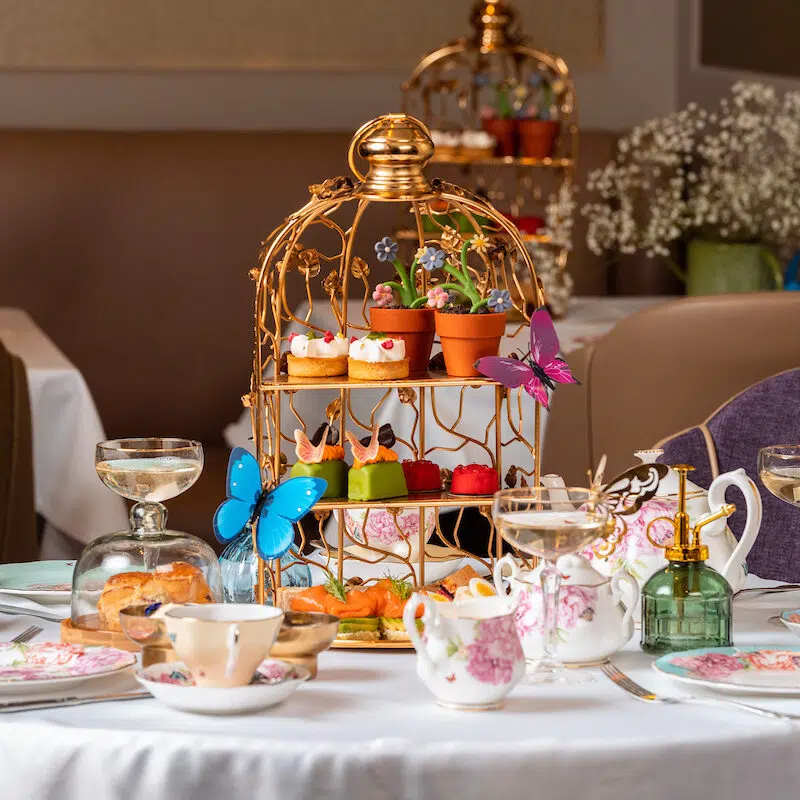 An elegant English afternoon tea service with gilded tiered stand, pastries, and porcelain teaware